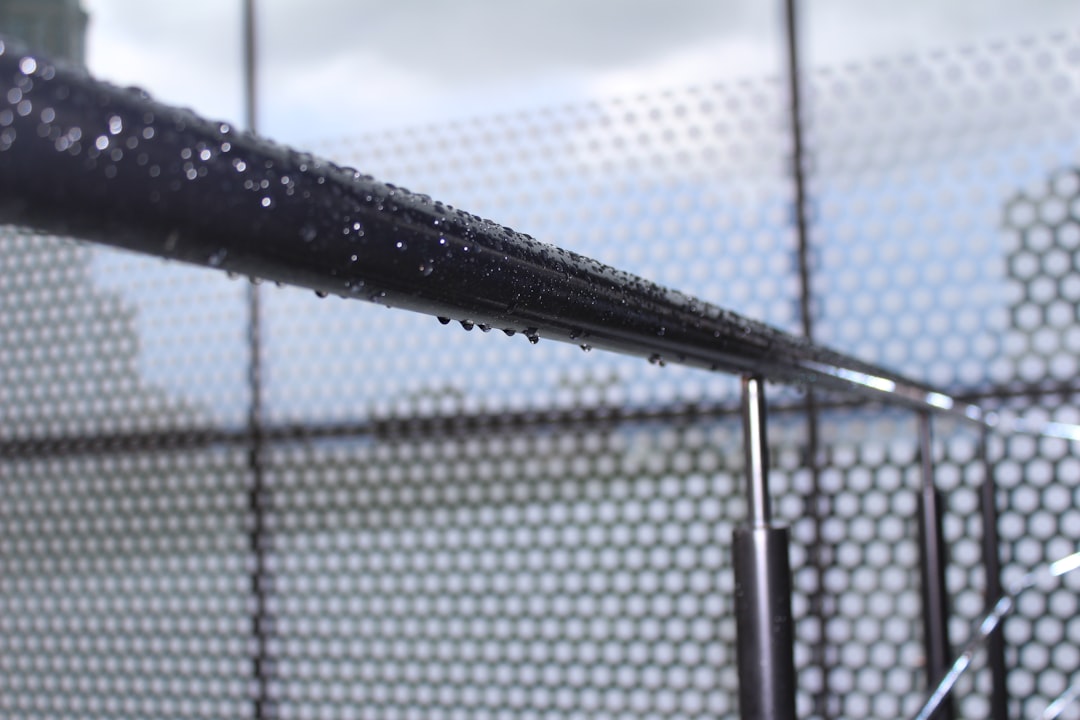 a-close-up-of-a-metal-fence-with-water-droplets-on-it-kuxuc92i46q
